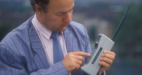 A man using an old mobile phone from the 1980s