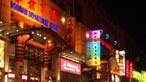 A lit up shopping street by night.