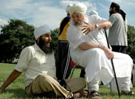 Sikh adult and old man sitting outside, talking and laughing
