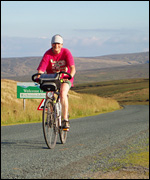 Cyclist riding from Swaledale into Cumbria