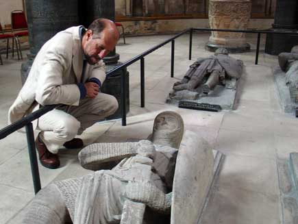 Martin Palmer looks down at the carving of a fully-armoured stone knight on the top of a tomb