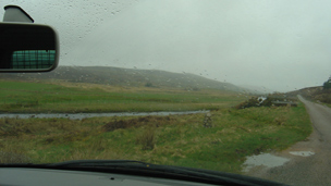 Rainy view through car windscreen of path and flat land at Forsinard Flows.