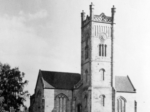 Church with central square tower standing in open fields.