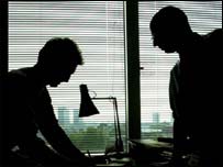 Two men talking in darkened office