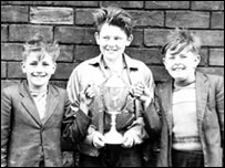 Three young boys holding a trophy