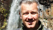Derek Brockway stood next to a waterfall