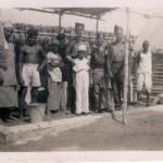 Some of the boys with natives outside the cookhouse.