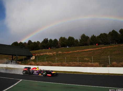 A Formula 1 racing car drives past a rainbow