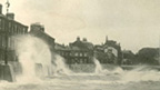 Black and white view of Stuart Street, Millport showing large storm waves breaching the sea wall.
