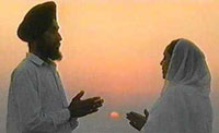 A man and woman praying in white garments at sunrise