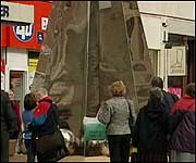 People examining the riddle statue