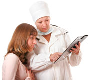 A middle-aged doctor in white coat explains the contents of a medical chart to her patient, a teenage girl. Photo by Oleg Prikhodko
