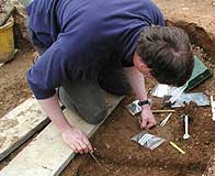 an archaeologist digging and recording a find