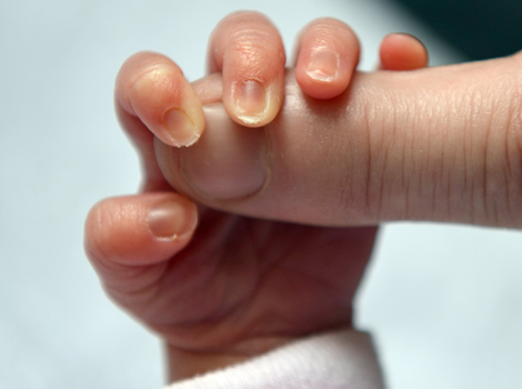 A baby holds its mother's finger