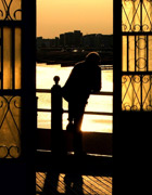Silhouette of a person leaning on a railing during a sunset, thinking