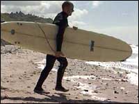 Man carrying a surfboard on the beach