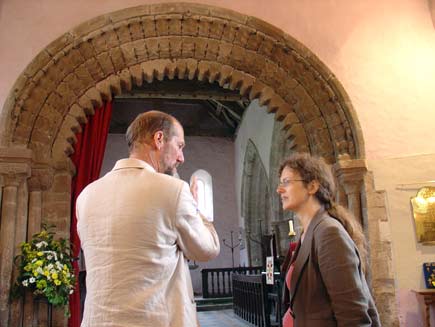 Martin Palmer (left) with Helen Nicholson inside a church looking at a Templar arched doorway of crenellated brown stone