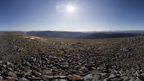 View from the rocky top of Beinn Bheoil towards other mountains on a clear, sunny day.