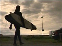 silhouette of surfer and board walking in car park