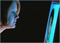 Woman inspecting a male face on a computer monitor