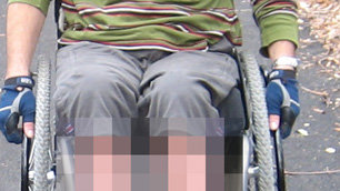 Tim in his wheelchair with his legs pixellated