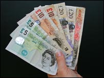Hand holding money. Five, ten, twenty and fifty pound notes.