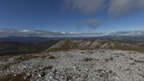 View from the rocky top of Beinn Iutharn Mhor towards other mountains on a clear, sunny day.