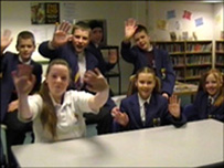 pupils in library wave at camera