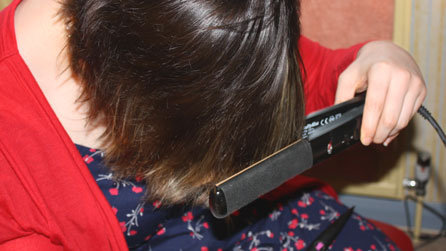 Head down, Nicola begins 'ironing her fringe' with the hair straighteners - though the non-slip handle helps considerably